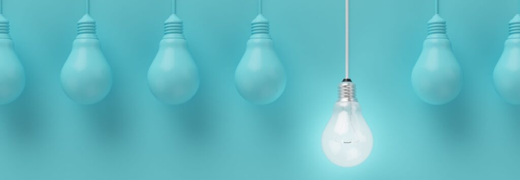 Leadership concept. Hanging light bulbs with glowing one different idea on light blue background , Minimal concept idea , flat lay , top